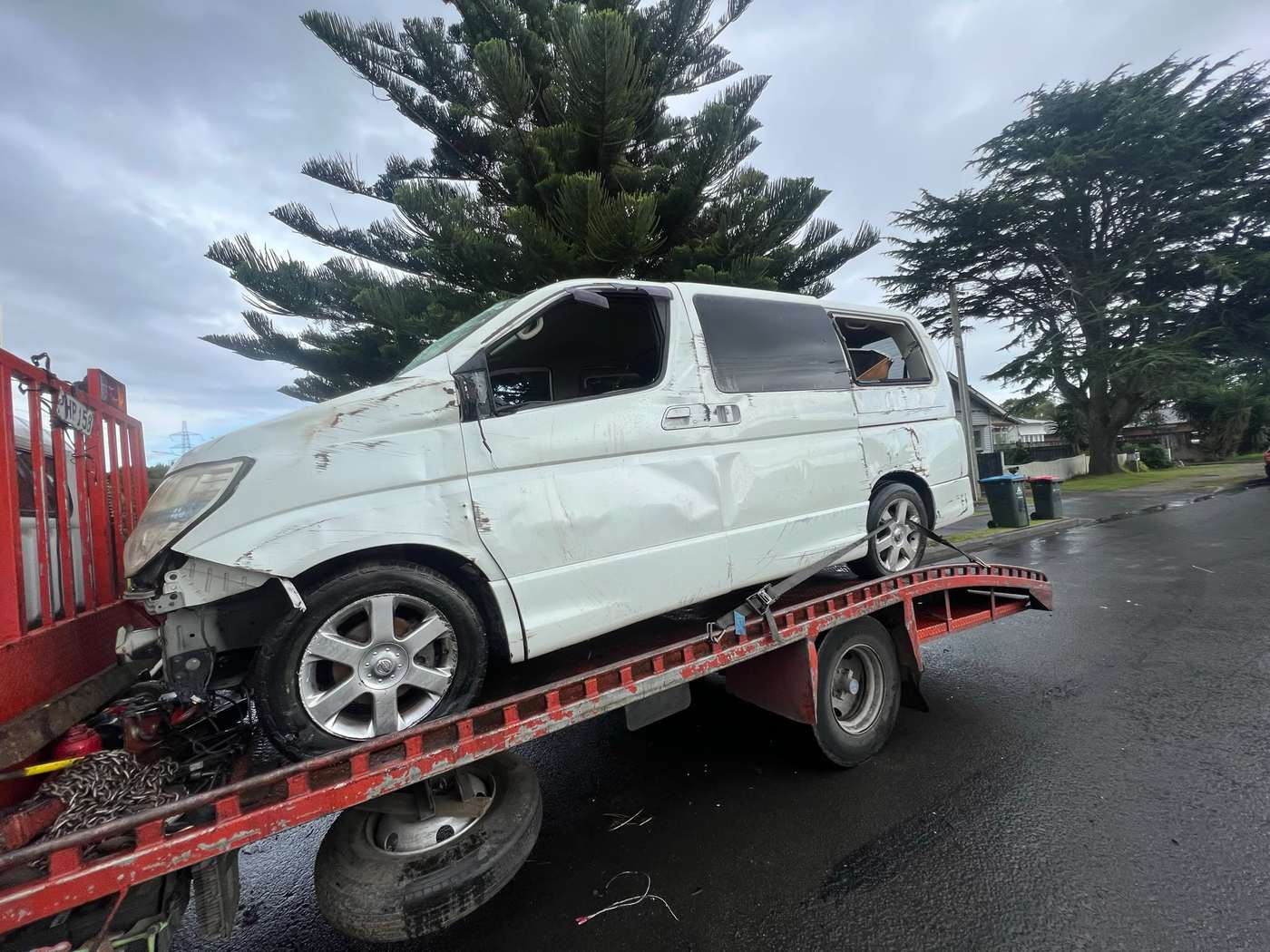 Damaged white van loaded on a red tilt-tray truck for removal in Queenstown