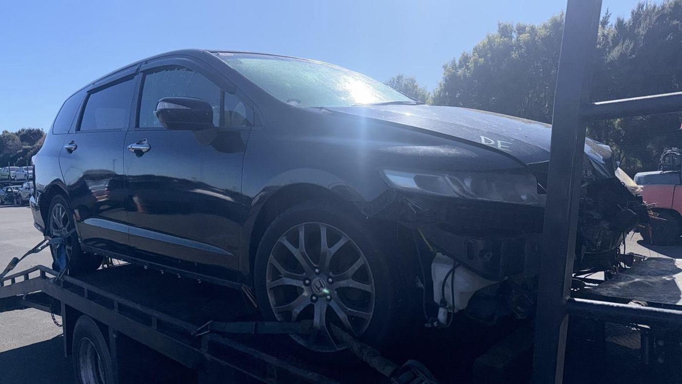 Crash-damaged black people-mover with front-end accident damage on a recovery truck