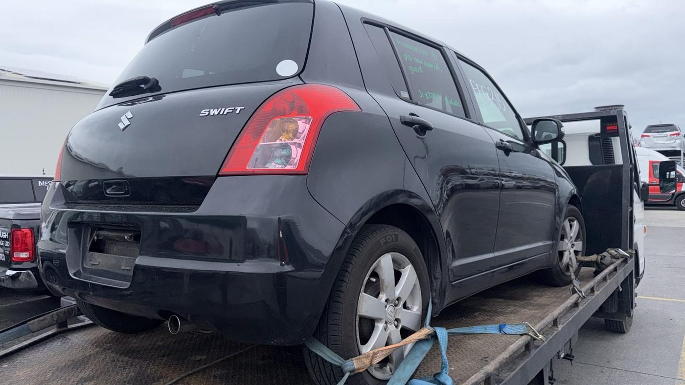 Black Suzuki Swift strapped onto a tow truck being collected in Queenstown